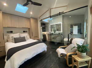 Bedroom featuring lofted ceiling with skylight, recessed lighting, dark wood finished floors, and a ceiling fan