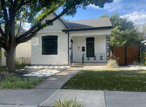 Bungalow featuring a porch, roof with shingles, a front yard, and fence