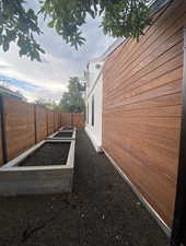 View of side of property featuring a fenced backyard and a garden