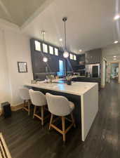 Kitchen with a peninsula, a kitchen breakfast bar, light countertops, and decorative light fixtures