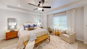 Bedroom with baseboards, a raised ceiling, and light colored carpet