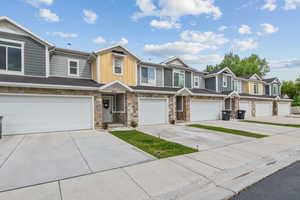 Townhome / multi-family property featuring board and batten siding, driveway, an attached garage, and stone siding, no backyard neighbors