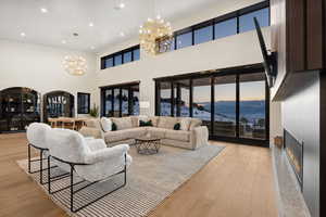 Living area with a chandelier, a lit fireplace, light wood finished floors, and a wealth of natural light