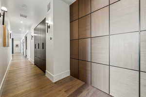 Hall with light wood-style flooring, visible vents, and baseboards