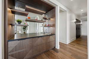 Bar featuring indoor wet bar, recessed lighting, a sink, wood finished floors, and baseboards