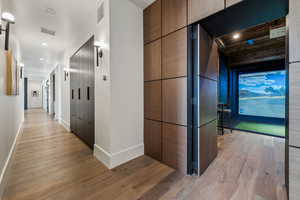 Corridor with light wood-style flooring, visible vents, baseboards, and a barn door