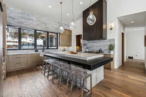 Kitchen featuring dark wood-style floors, light countertops, a kitchen island, modern cabinets, and a kitchen bar