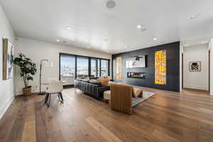 Living area with baseboards, a glass covered fireplace, wood finished floors, and recessed lighting