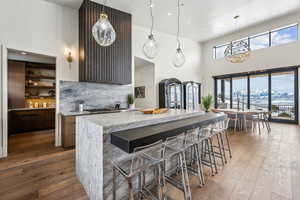 Kitchen with light stone counters, a breakfast bar, decorative light fixtures, a mountain view, and wood finished floors