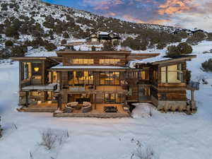 Snow covered rear of property with stone siding, an outdoor fire pit, and a mountain view