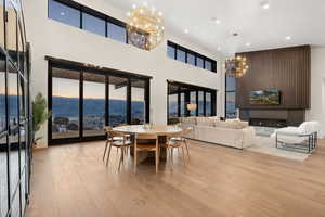 Dining area with an inviting chandelier, light wood-style flooring, plenty of natural light, and a glass covered fireplace