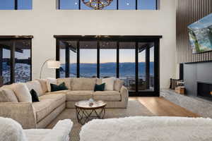 Living room with an inviting chandelier, a towering ceiling, a premium fireplace, and wood finished floors