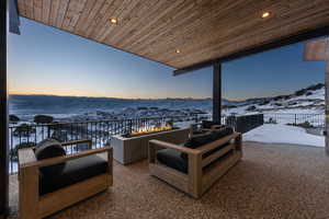 Snow covered patio with an outdoor living space with a fire pit and a mountain view