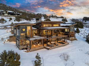 Snow covered back of property with a chimney and an outdoor hangout area