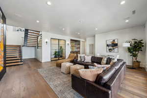 Living room featuring recessed lighting, visible vents, stairway, and wood finished floors