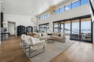 Living room featuring recessed lighting, wood finished floors, a towering ceiling, and an inviting chandelier