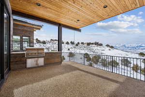 Snow covered patio with a mountain view, grilling area, and area for grilling