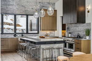 Kitchen with light wood-type flooring, double oven range, brown cabinetry, modern cabinets, and pendant lighting