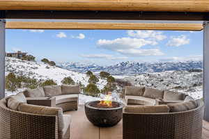 Snow covered patio with a mountain view and an outdoor living space with a fire pit