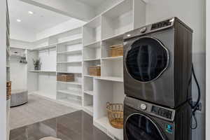 Laundry room featuring marble finish floor, stacked washer and dryer, laundry area, and recessed lighting