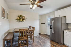 Dining area with dark wood-style floors, ceiling fan, and baseboards