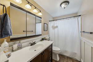 Bathroom with curtained shower, vanity, toilet, and wood finished floors