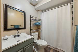 Full bath with a shower with shower curtain, vanity, toilet, and wood finished floors