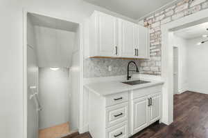 Kitchen with dark wood-style flooring, light countertops, white cabinets, a sink, and baseboards