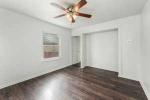 Unfurnished bedroom featuring dark wood-style flooring, a ceiling fan, and baseboards