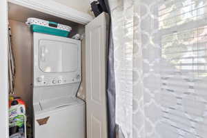 Clothes washing area featuring stacked washer and dryer