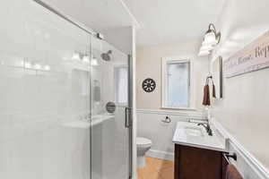 Bathroom featuring vanity, a shower with door, tile patterned floors, and toilet