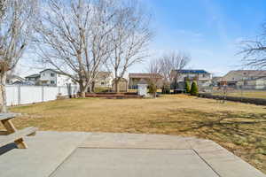 View of yard featuring a storage shed, a fenced backyard, a residential view, an outbuilding, and a patio area