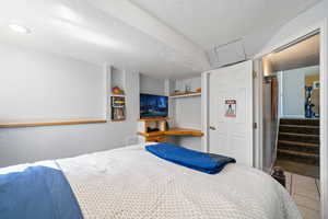 Bedroom with tile patterned flooring, a textured wall, and a textured ceiling