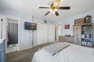 Bedroom with baseboards, a ceiling fan, ensuite bathroom, dark colored carpet, and a closet