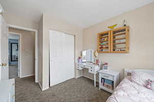 Bedroom featuring a closet, dark carpet, and baseboards