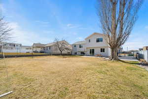 Rear view of house with a fenced backyard, a lawn, and a patio