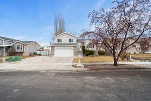 View of front of property featuring an attached garage, brick siding, fence, driveway, and a residential view