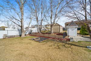 View of yard featuring a residential view, fence, an outdoor structure, and a shed