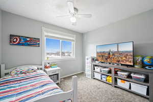 Bedroom with a ceiling fan, carpet flooring, a textured ceiling, and baseboards