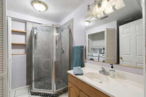 Bathroom with a textured ceiling, vanity, visible vents, and tile patterned floors