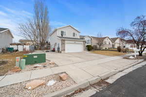 View of front of home featuring driveway, a garage, a residential view, fence, and brick siding