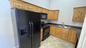 Kitchen featuring black appliances, a sink, and dark countertops