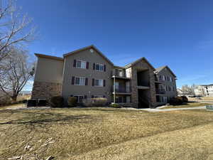 Rear view of house featuring a yard and central AC unit