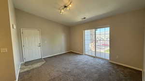 Empty room with lofted ceiling, dark colored carpet, and baseboards