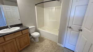 Bathroom with a textured wall, toilet, vanity, and tub / shower combination