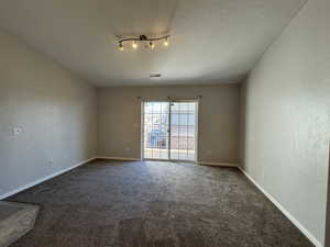 Empty room with a textured ceiling, carpet, visible vents, and baseboards