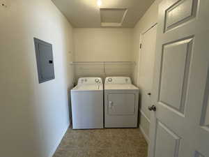 Washroom featuring light tile patterned floors, laundry area, separate washer and dryer, baseboards, and electric panel