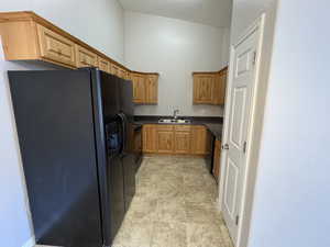 Kitchen featuring dark countertops, brown cabinets, a sink, and black appliances