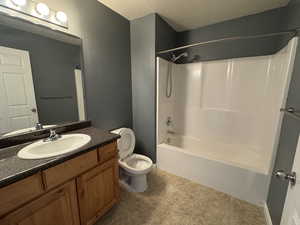 Full bath featuring toilet, tile patterned floors, a textured ceiling, vanity, and shower / washtub combination