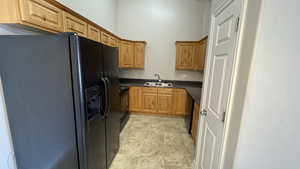 Kitchen with black appliances, dark countertops, a sink, and brown cabinetry